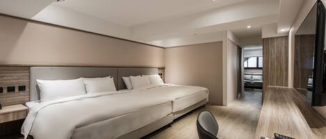 A modern hotel room with a large bed, a desk with a chair, and a flat-screen TV.