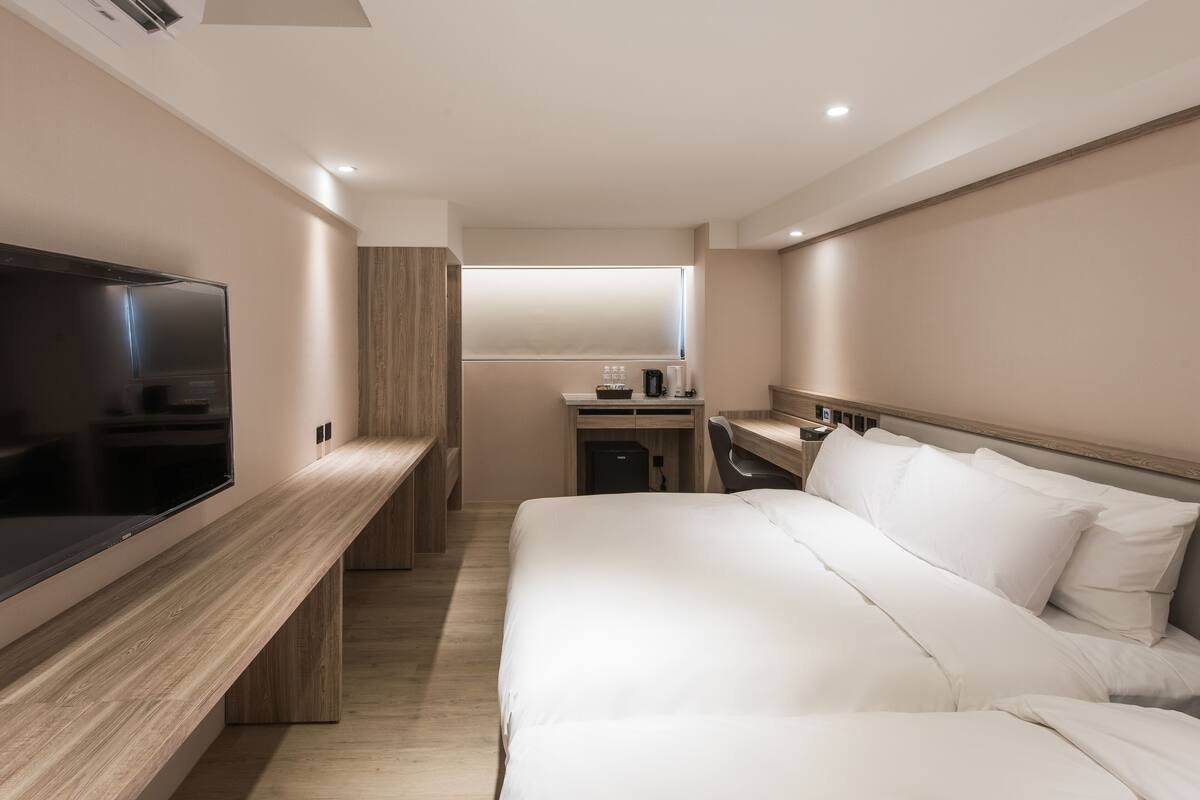 Ein modernes Hotelzimmer mit einem großen Bett, einem Flachbildfernseher, einem Schreibtisch und einem Fenster.