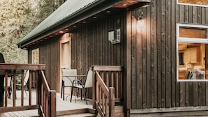 A wooden cabin with a porch, outdoor seating, and a visible kitchen area. - 75sl - 2-bdrm - Loft - Sleeps 6 - Wifi - Pets Ok (Deming)