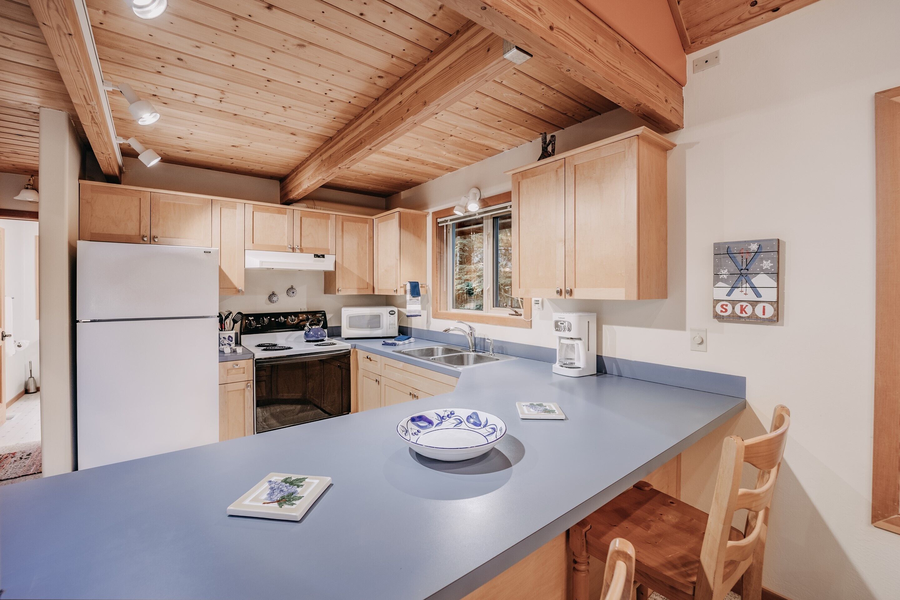 A modern kitchen with wooden cabinets, a large island, and a window.