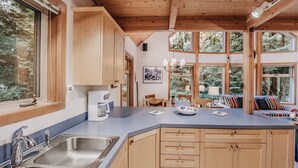 A modern kitchen with wooden cabinets, a large island, and a view of the forest through large windows. - 75sl - 2-bdrm - Loft - Sleeps 6 - Wifi - Pets Ok (Deming)