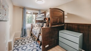 A bedroom with a bunk bed, a dresser, and a patterned rug. - 80mbr - Hot Tub - Wifi - BBQ - Wood Stove - Sleeps 7! (Deming)