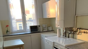 A kitchen with a window, a microwave, a coffee maker, a dishwasher, and an oven. - Mitten im Herzen von Hannover (Hannover)