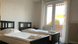 A hotel room with two single beds, a small table, and a window with curtains. - Mitten im Herzen von Hannover (Hannover)