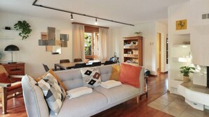 Una sala de estar moderna con un sofá gris, piso de madera y una zona de comedor con una mesa y sillas.
