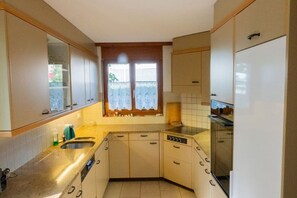 A compact kitchen with a window, white cabinets, a sink, and a dishwasher.