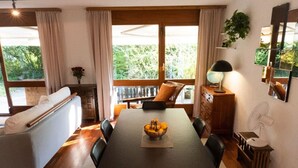 Comedor con mesa, sillas, un bol de fruta, un sofá y vistas al exterior.