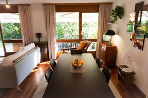 Comedor con mesa, sillas, un bol de fruta, un sofá y vistas al exterior.