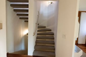 Un escalier dont les marches sont recouvertes de moquette, menant à un palier.
