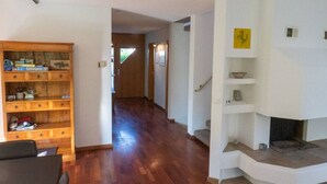 Amplia sala de estar con una estantería de madera, una chimenea y un pasillo que conduce a otra habitación.