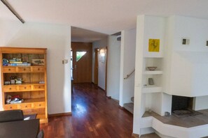Amplia sala de estar con una estantería de madera, una chimenea y un pasillo que conduce a otra habitación.