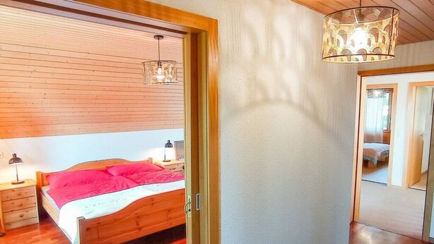 Un dormitorio con cama de madera, mesita de noche, lámpara y lámpara colgante.