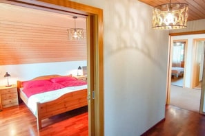 Un dormitorio con cama de madera, mesita de noche, lámpara y lámpara colgante.