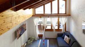 Un salón acogedor con techo de madera, un sofá, una mesa de centro y un ventanal con cortinas.