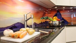 Una cocina de diseño moderno, con un lavamanos, una tabla de cortar con verduras y un salpicadero decorativo.