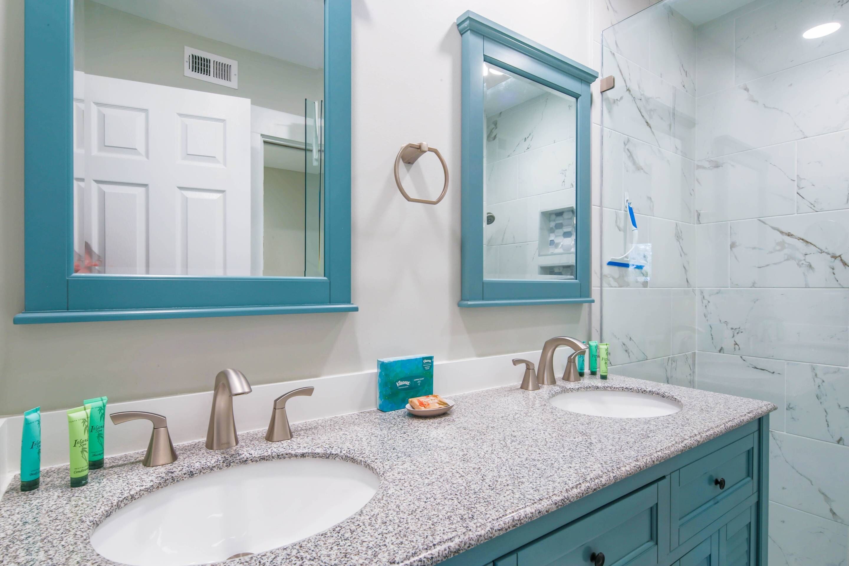 A bathroom with two sinks, a mirror, and a towel ring.