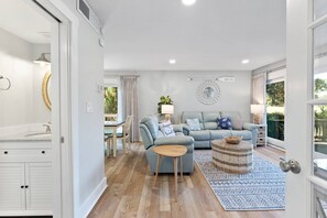 Relax in this stylish living room with a sofa, coffee table, and rug, offering a view of lush greenery.