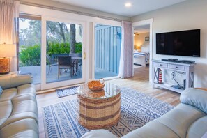 Relax in this stylish living room with a sofa, flat-screen TV, and sliding glass door to an outdoor dining area.