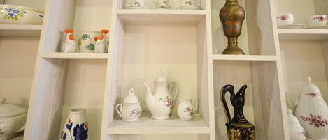 A display of various ceramic tea sets and vases on shelves.