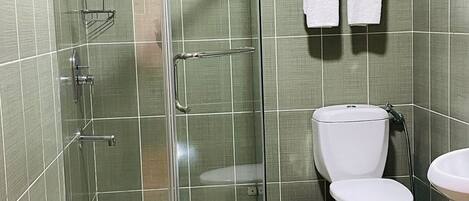 A bathroom with a glass-enclosed shower, a toilet, a sink, and a towel rack with towels.