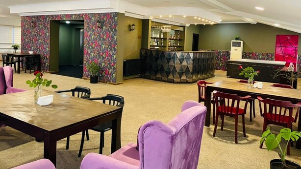Un vestíbulo de hotel con zona de bar, asientos y mostrador de recepción.
