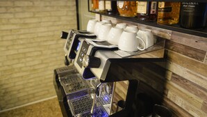 Una cafetera con diversas opciones de preparación y una variedad de licores sobre un estante de madera.