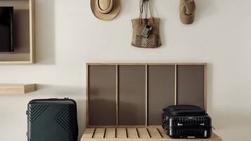 A room with a wooden bench, two suitcases, a hat, and a handbag on the wall.