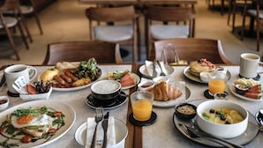 Un desayuno con diferentes platos, como huevos, tostadas, fruta y bebidas.