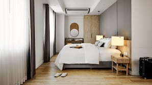 Una habitación de hotel moderna con una cama grande, lámparas de noche, un cabecero de madera, una mesita de noche con una bandeja y una maleta.