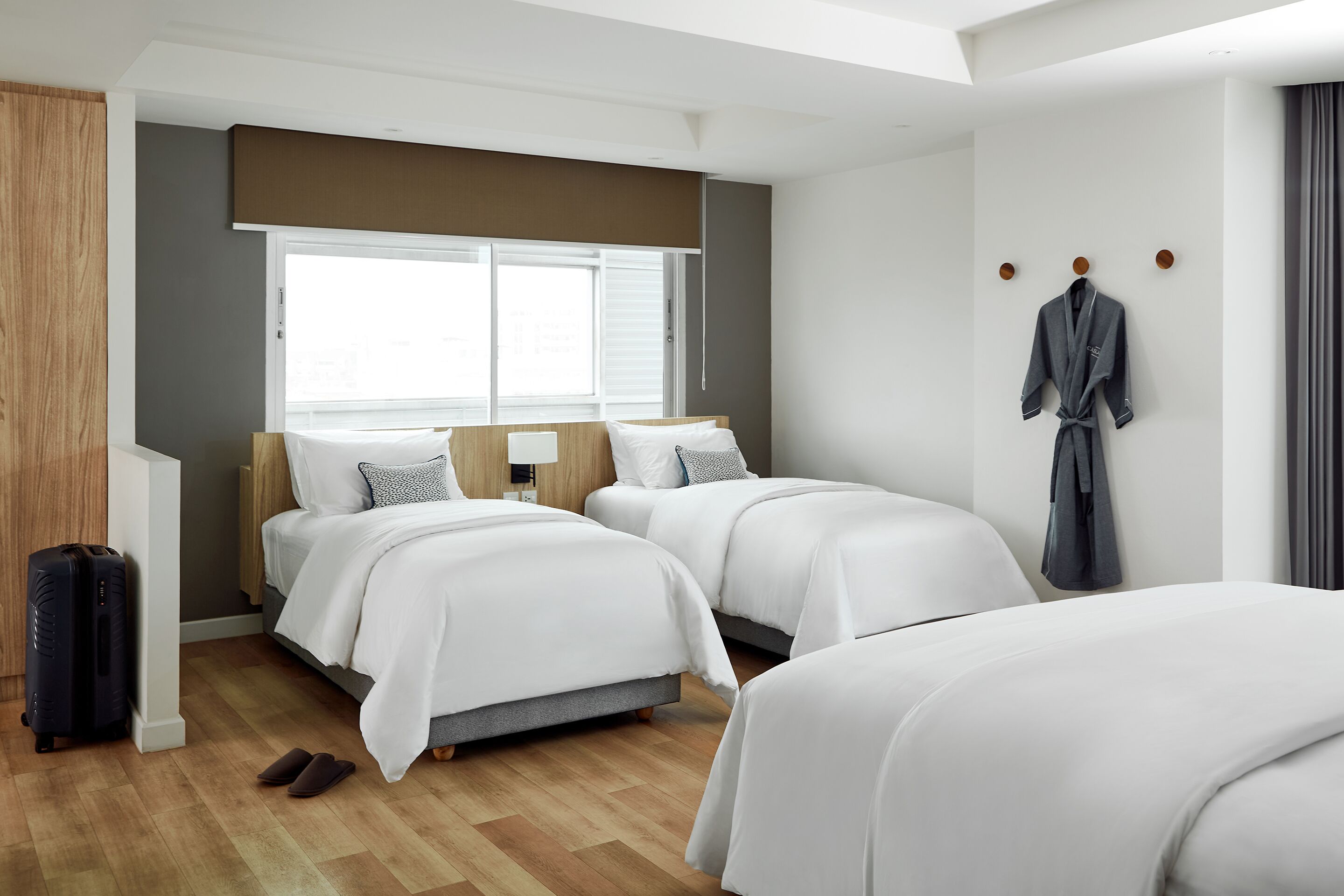 A hotel room with two beds, a suitcase, and a robe hanging on the wall.