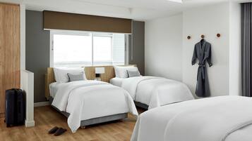 A hotel room with two beds, a suitcase, and a robe hanging on the wall.