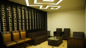 A modern living room with a sofa, chairs, and a glass coffee table. - Hotel SSV Grand (Hyderabad)