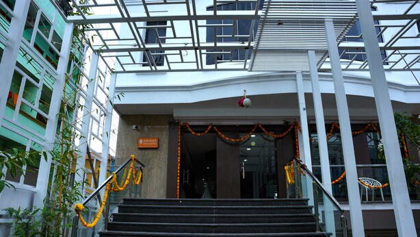 A building entrance with a staircase, glass railings, and decorative garlands. - Hotel SSV Grand (Hyderabad)