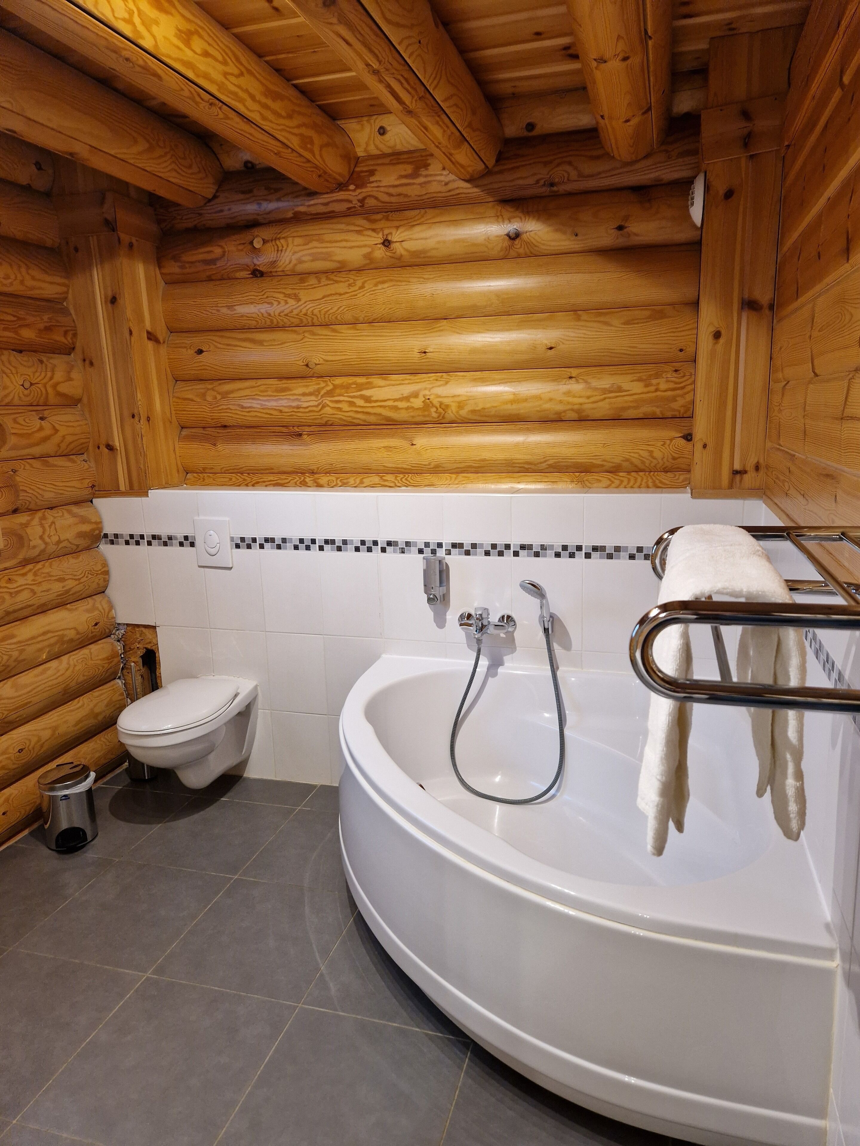 A bathroom with a white bathtub, a toilet, and a shower.