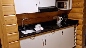 Cucina compatta con mobili bianchi, piano di lavoro nero, microonde e macchina per caffè.
