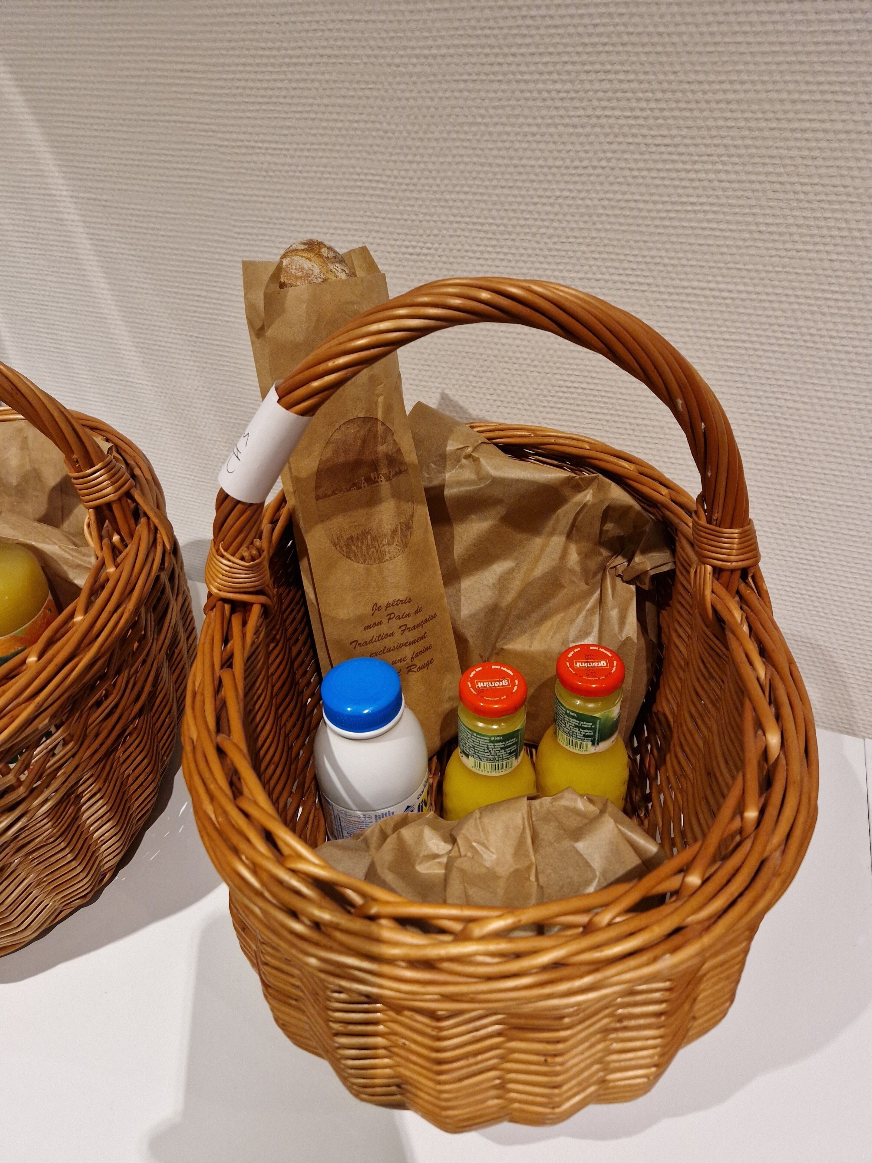Ein Korbbarn mit einer Flasche mit blauem Verschluss, zwei Flaschen mit roten Verschlusskappen und einem braunen Papiertüte.