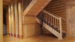 A wooden staircase with a handrail, a wooden door, and a glass vase with branches. - Les Pins Sylvestres (Amneville)