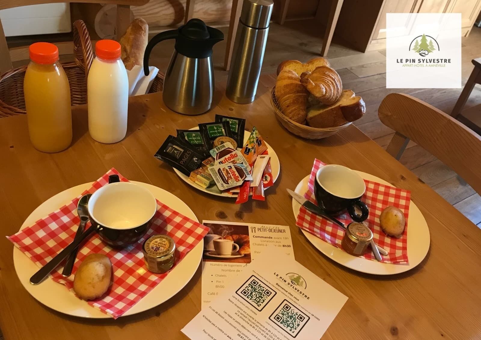 Aamiaispöytä, jossa on croissantteja, Nutellaa ja kahvia puupöydällä.