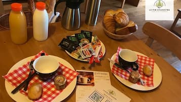 Aamiaispöytä, jossa on croissantteja, Nutellaa ja kahvia puupöydällä.