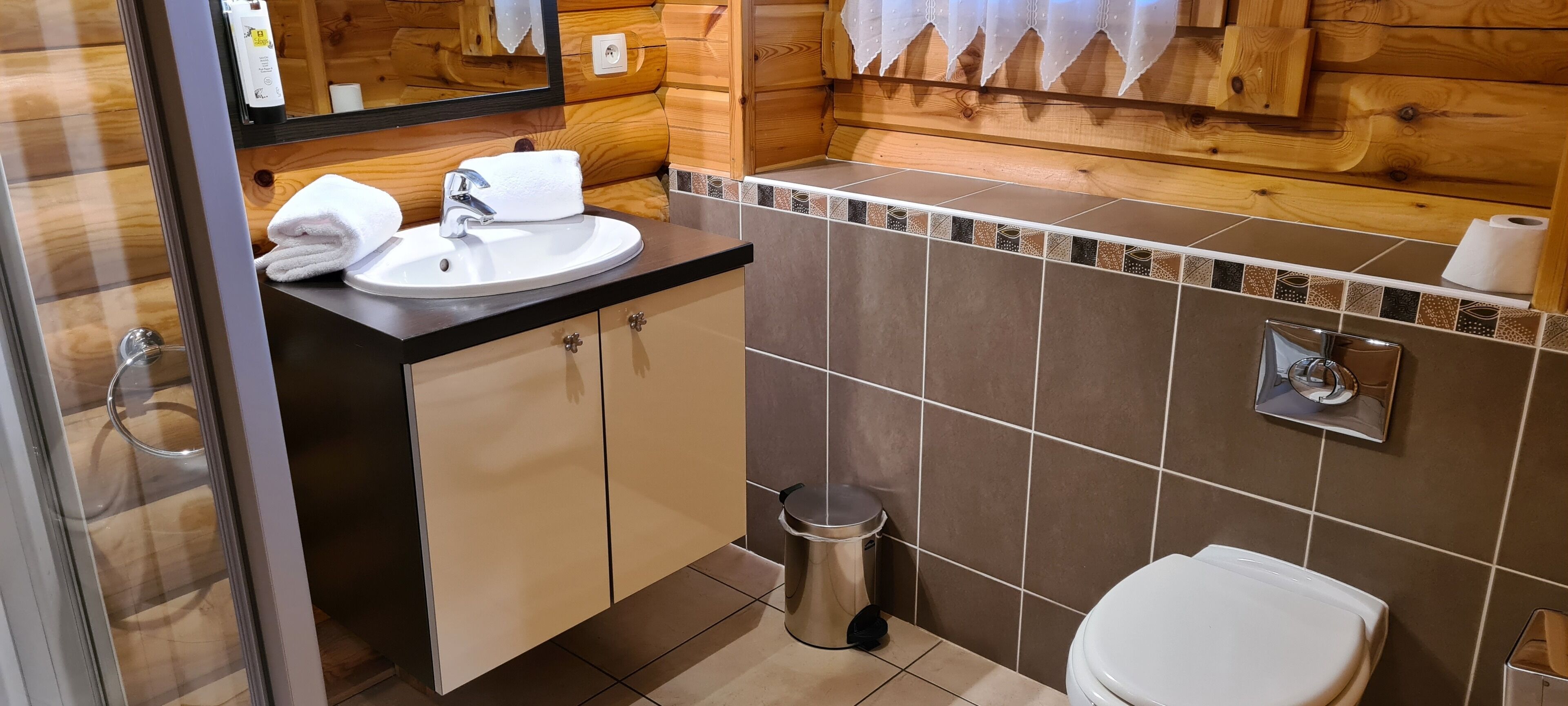 Un baño con paneles de madera, un lavabo, un espejo y un inodoro.
