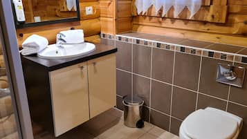 Un baño con paneles de madera, un lavabo, un espejo y un inodoro.