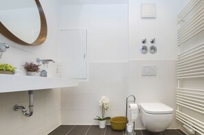 A modern bathroom with a white sink, mirror, toilet, and towel rack.
