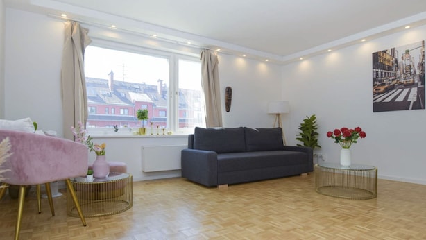 Un salon moderne avec un canapé gris, un fauteuil rose et une table basse ronde.