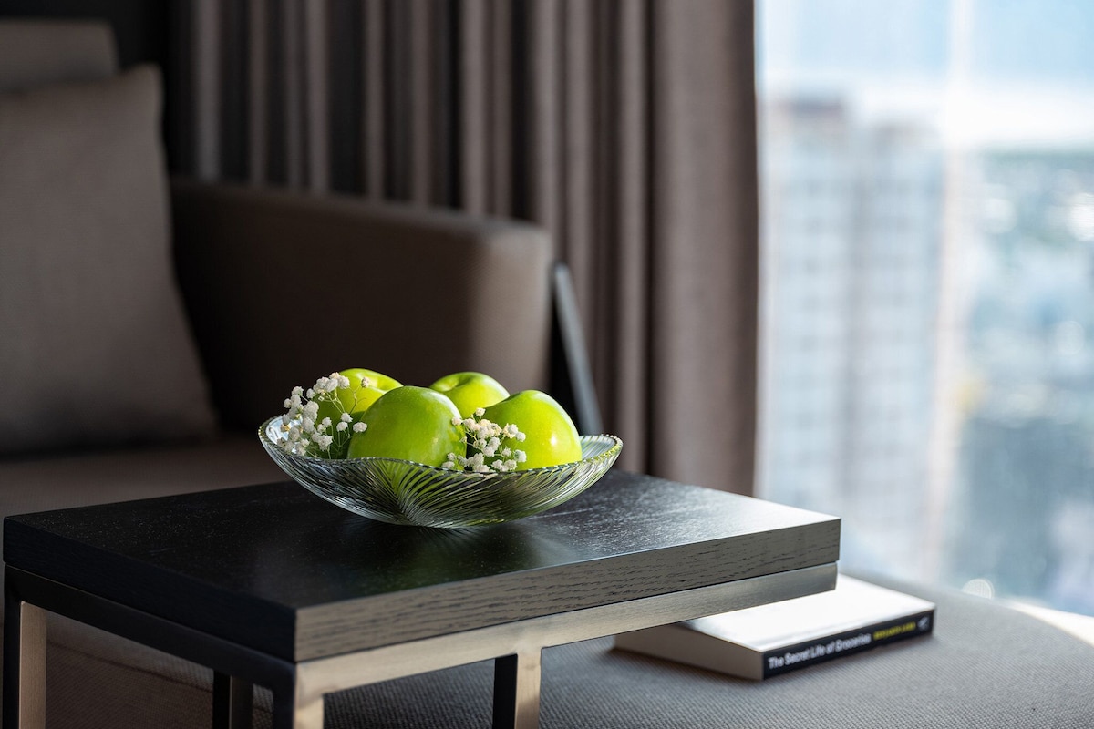 Un tazón de manzanas verdes sobre una mesa, con un libro a un lado.
