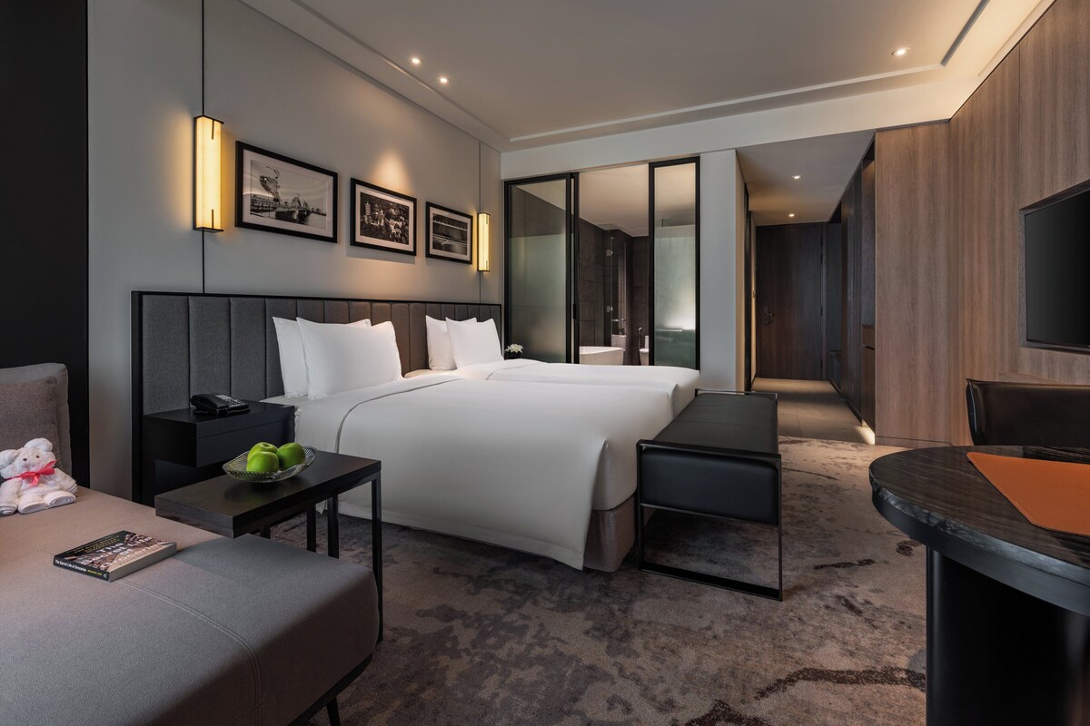 Una habitación de hotel moderna con una cama grande, mesitas de noche, un escritorio y una televisión de pantalla plana.