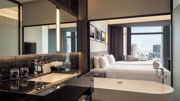 A modern hotel room with a large bed, a separate bathroom with a bathtub, a vanity with a mirror, and a city view.
