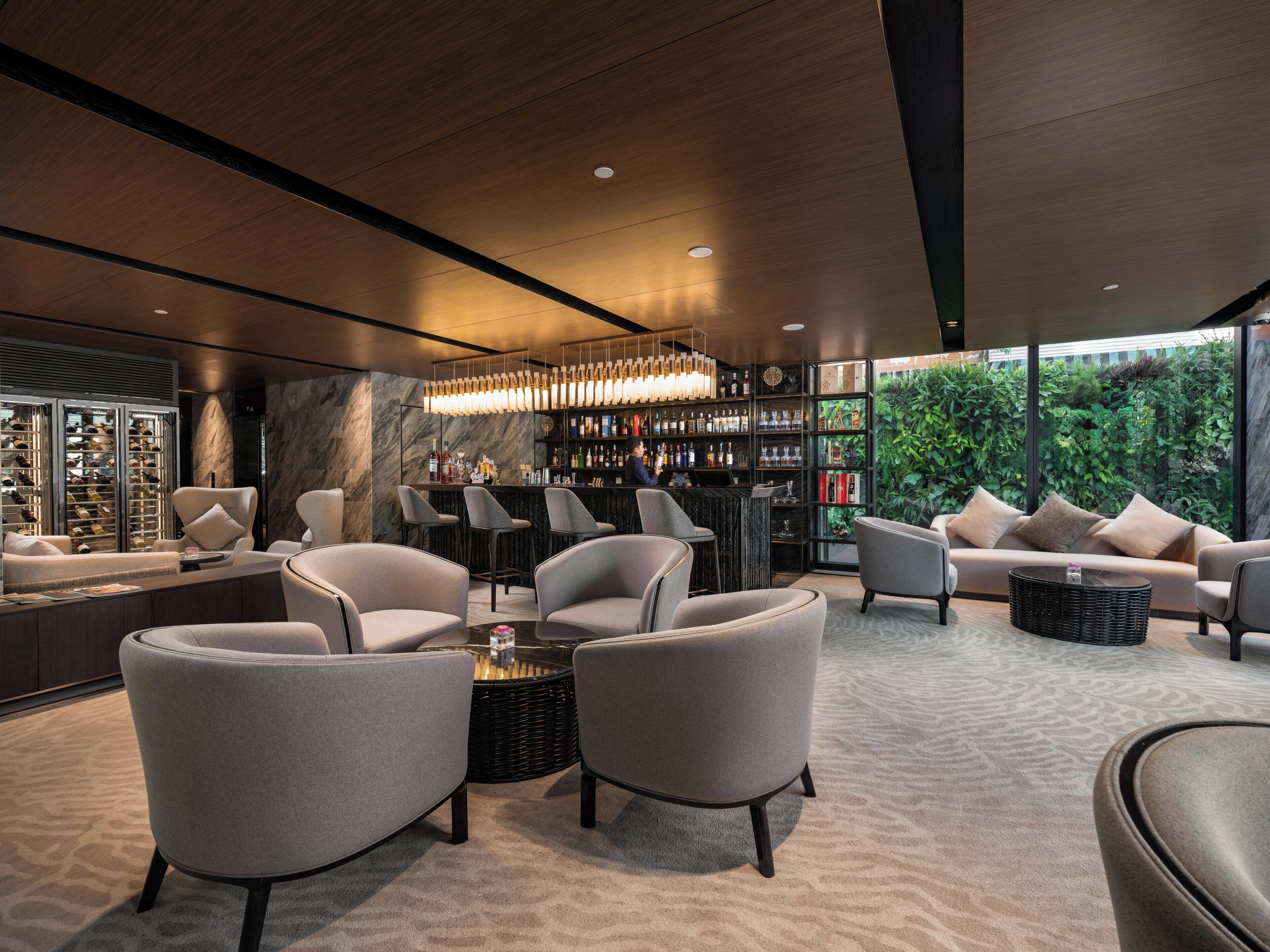 Een moderne lounge met een bar, zitplaatsen en uitzicht op groen.