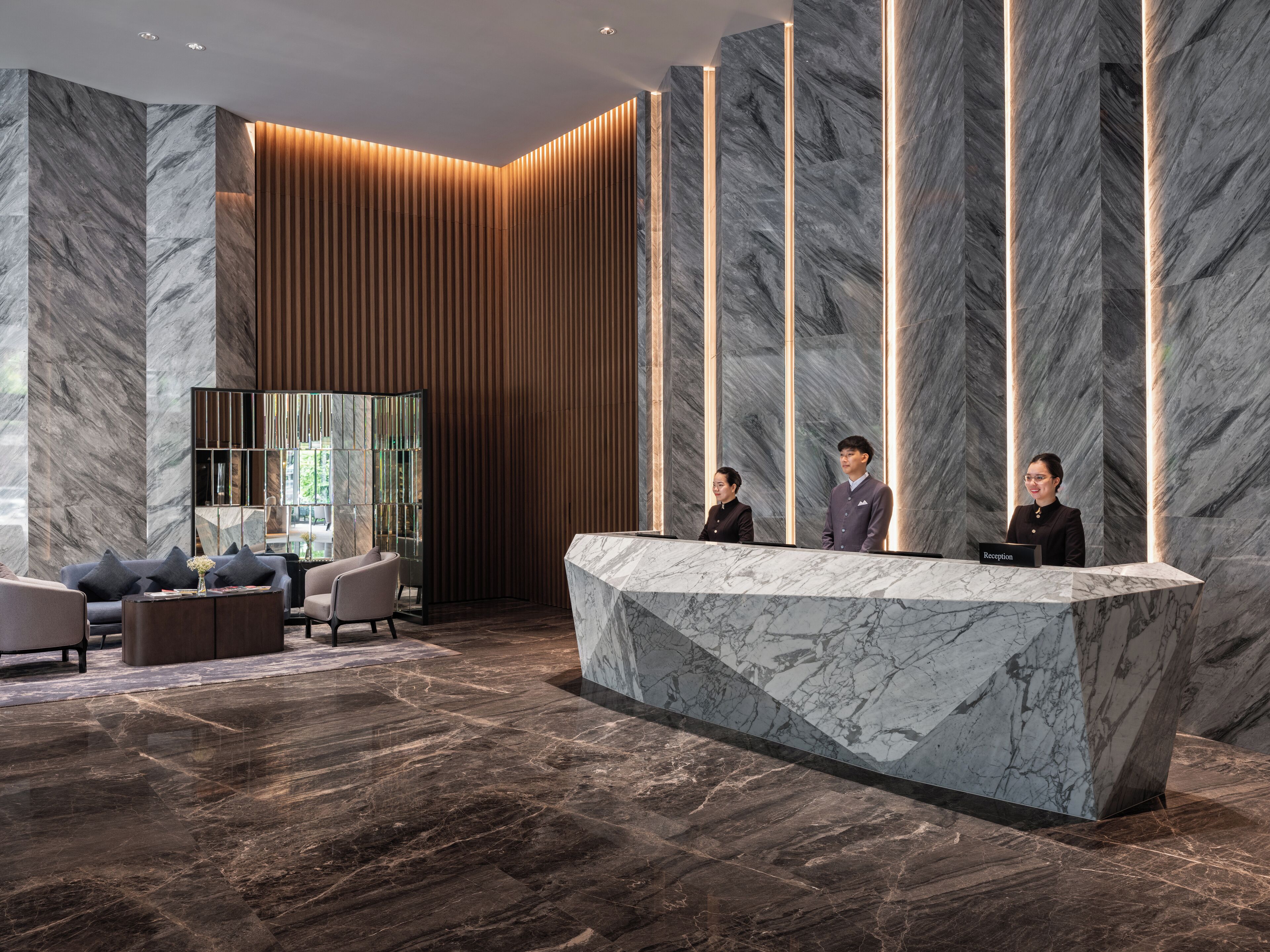 A reception area with a marble reception desk, modern furniture, and vertical lighting accents.