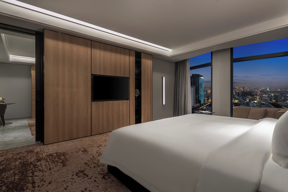 Una habitación de hotel moderna con una cama grande, televisión de pantalla plana y vista a la ciudad.