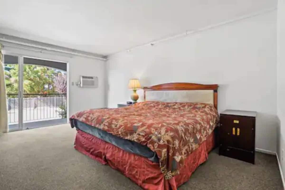 Un dormitorio con cama, mesita de noche, lámpara y armario.